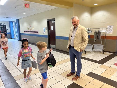 Principal greeting students in hallway at Mill Creek Elementary